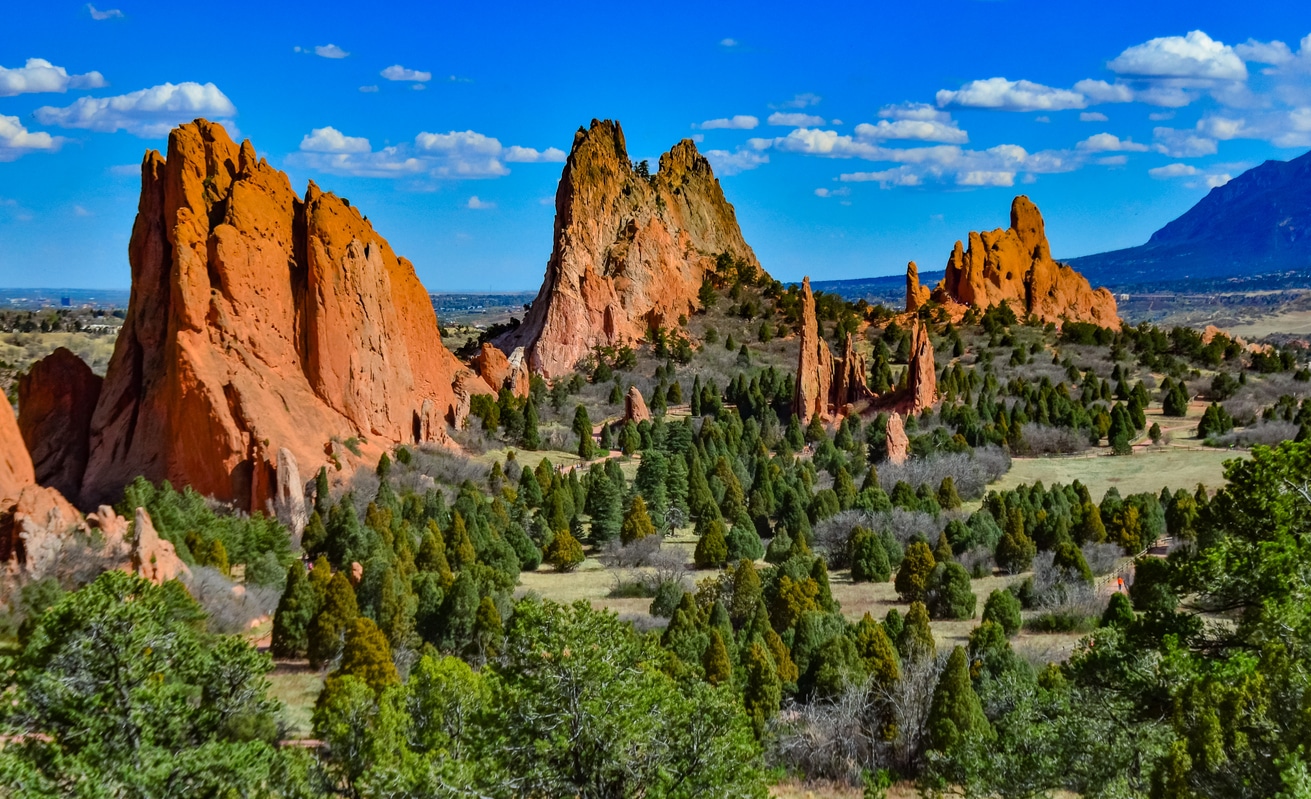 Red rock formations of Garden of the Gods in Colorado Springs under a bright blue sky with scattered clouds