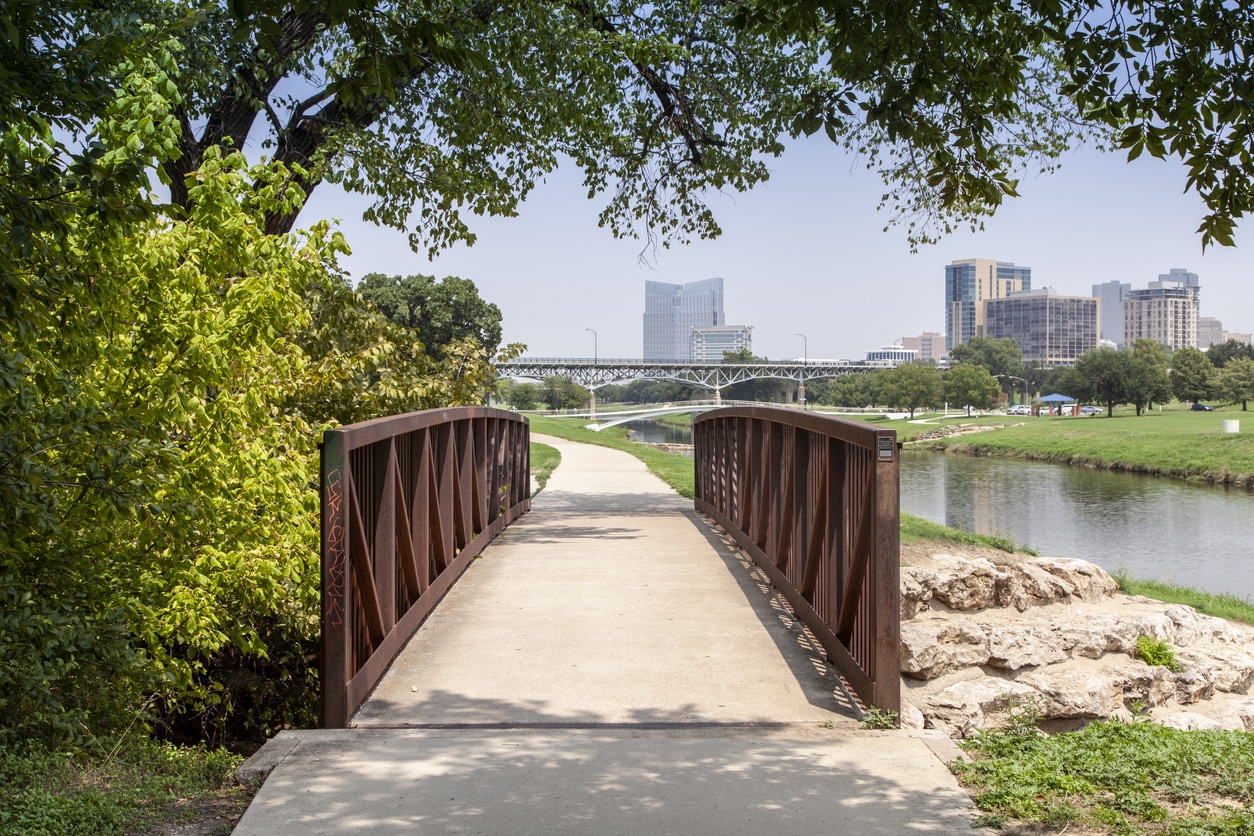 Trinity Park in the Fort Worth neighborhood of Downtown, with a bridge over the river and view of the city