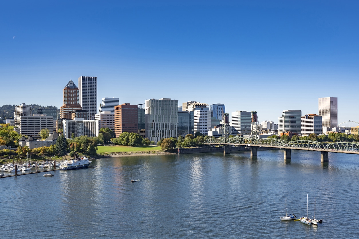 Portland Downtown with office and residential high-rise buildings on the waterfront of the Willamette River with a marina and an arched drawbridge over the river Portland high rises, Hawthorne Bridge, and boats on the Willamette River—a view awaiting those moving to Portland