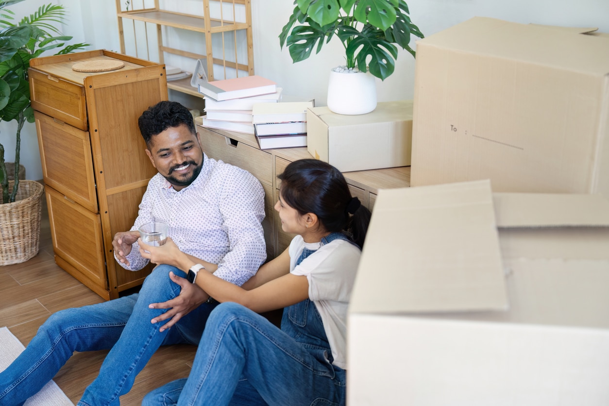 Married couple moving in new property bought together on mortgage loan Couple taking a water break from moving in the summer