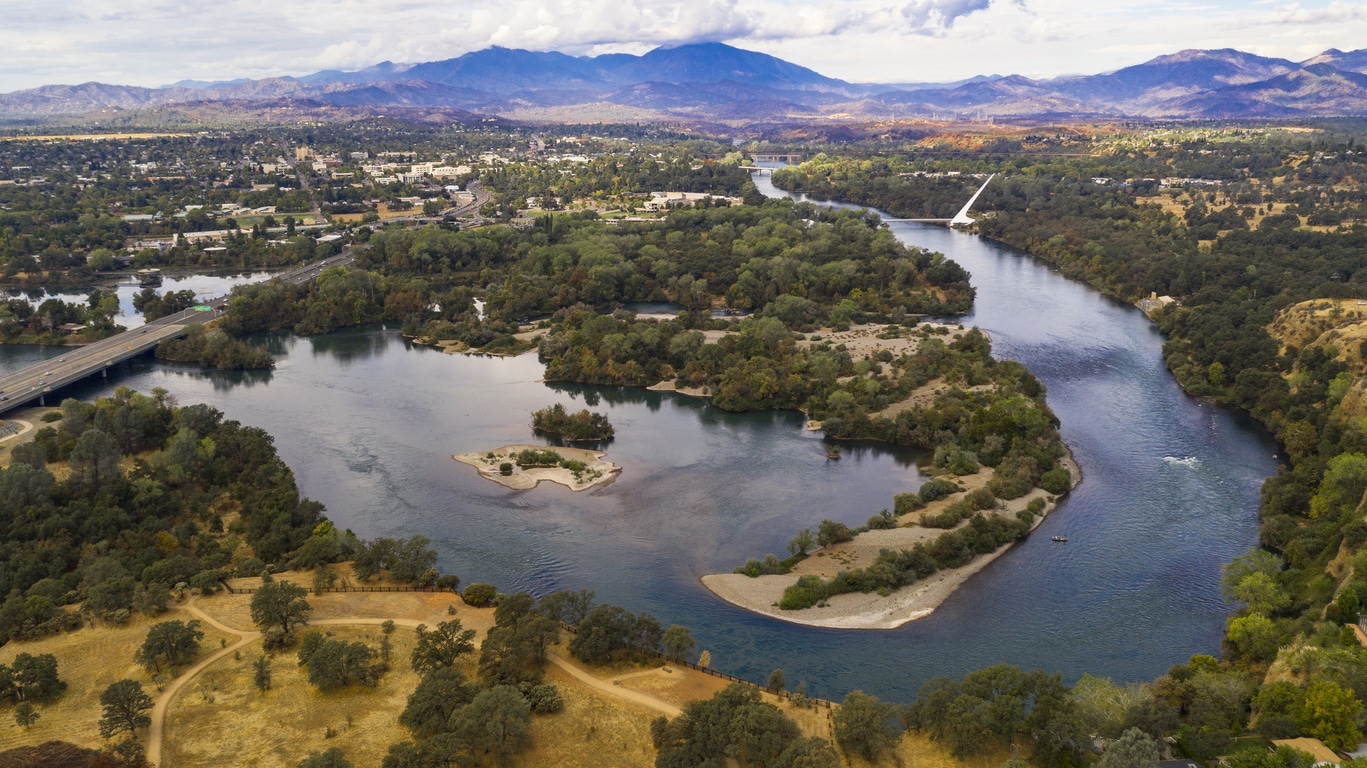 Aerial View Sacramento River Redding California Bully Choop Mountain A river flows under a bridge on a clear day in a Sacramento neighborhood