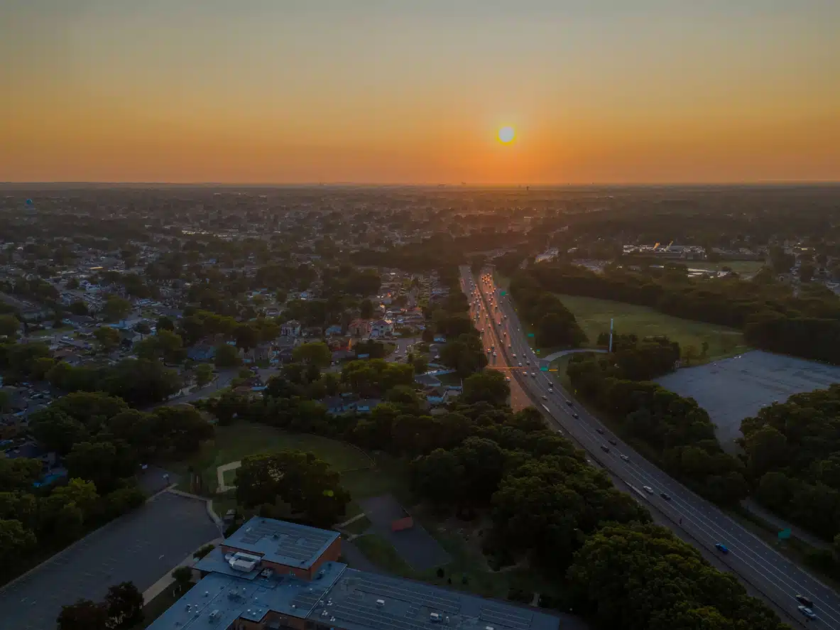 Southern State Parkway on Long Island, NY at sunrise, Valley Stream State Park with trees Aerial view of Southern State Parkway on Long Island, NY at sunset, with Valley Stream State Park and suburban homes