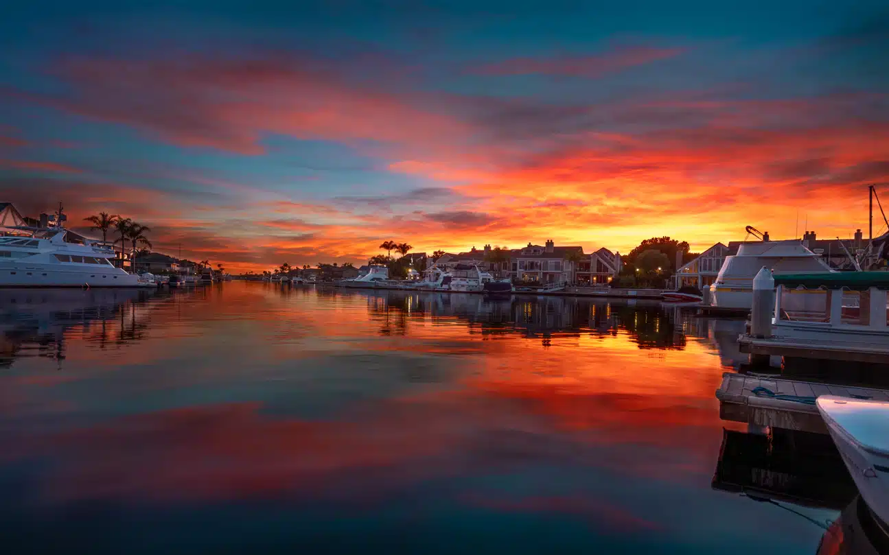 Vibrant sunset over the Long Island neighborhood of Huntington Beach Harbor, with boats docked along the waterfront