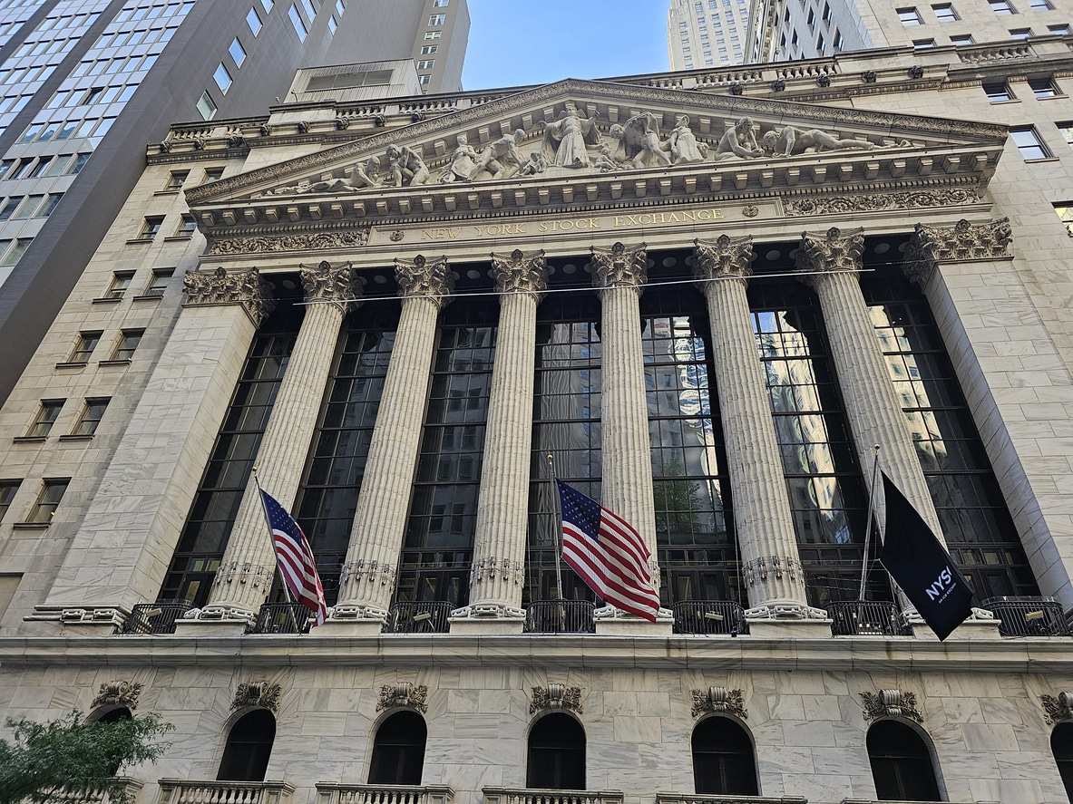 Facade of the New York Stock Exchange building on Broad Street, NYC, with American flags displayed