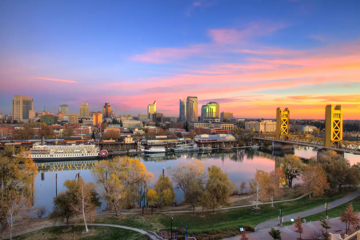 Sacramento skyline at sunset, featuring the Tower Bridge, a river, and city buildings