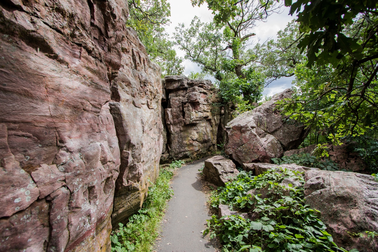 Circle Trail A narrow path winds through rocky cliffs and green foliage at Pipestone National Monument in the Midwest