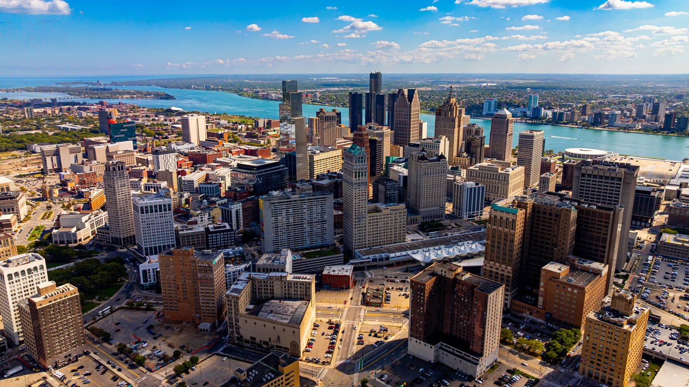 Detroit skyline at sunset with the Renaissance Center, glowing riverfront, and a docked riverboat
