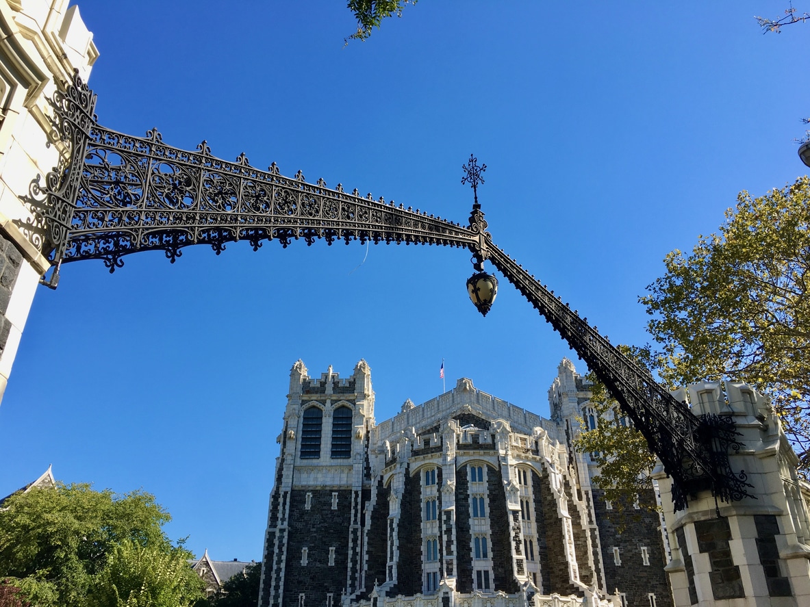 Shepard Hall at City College in Harlem, a gothic-style landmark, framed by green trees under a clear blue sky