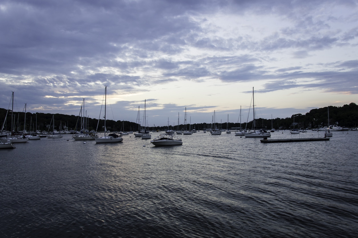 Boats docked in a Long Island harbor at dusk, a beautiful sight for those moving to Long Island