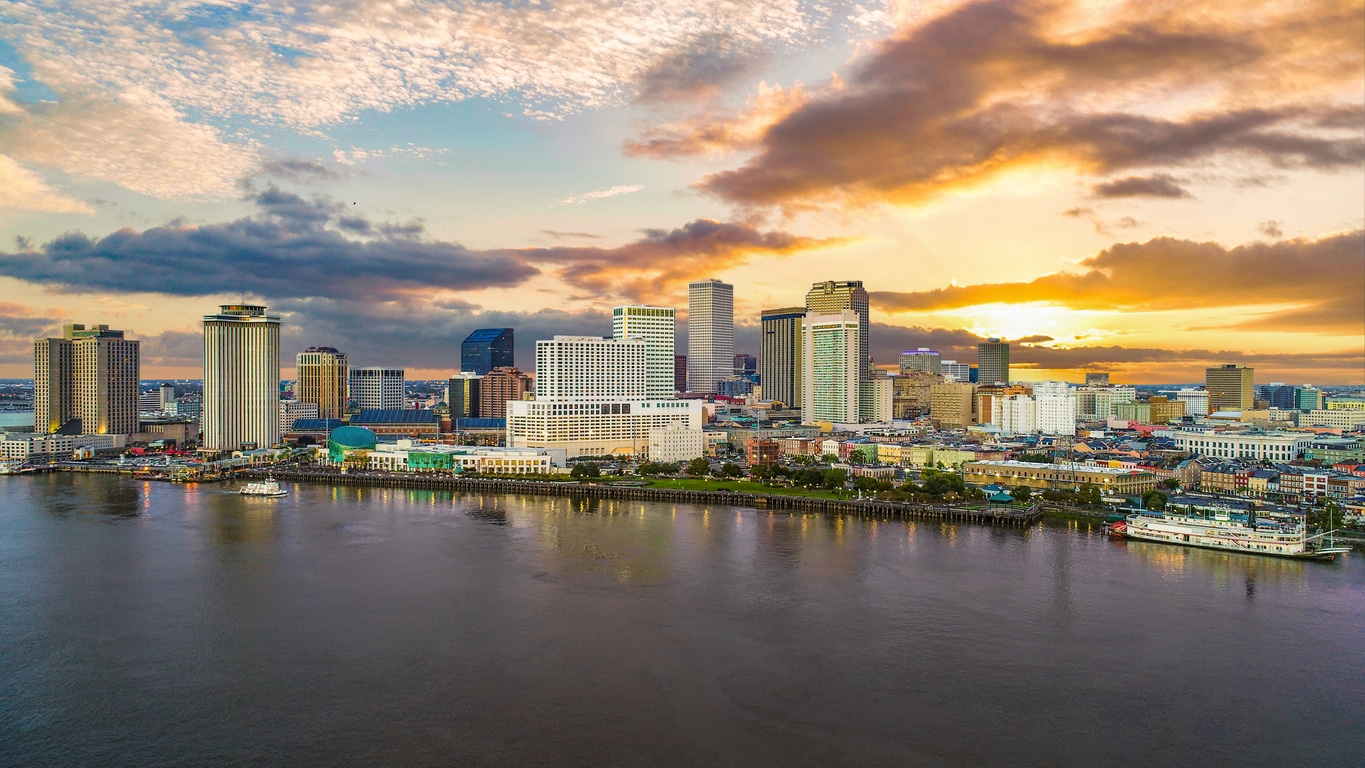 New Orleans skyline and Mississippi River at sunset with colorful clouds and downtown buildings