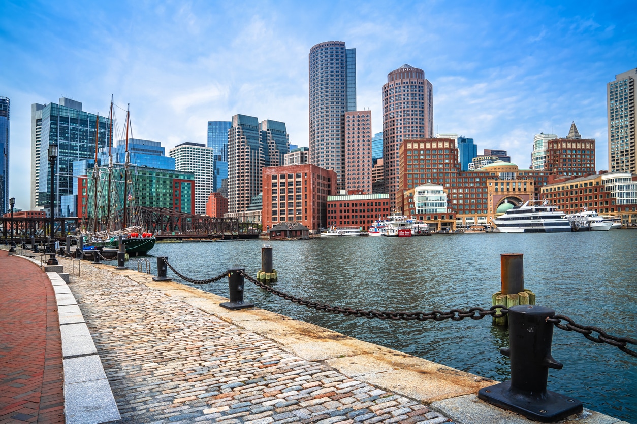 Boston Harborwalk with cobblestone path, historic ships, and modern skyline, a scenic spot for those moving to Massachusetts 