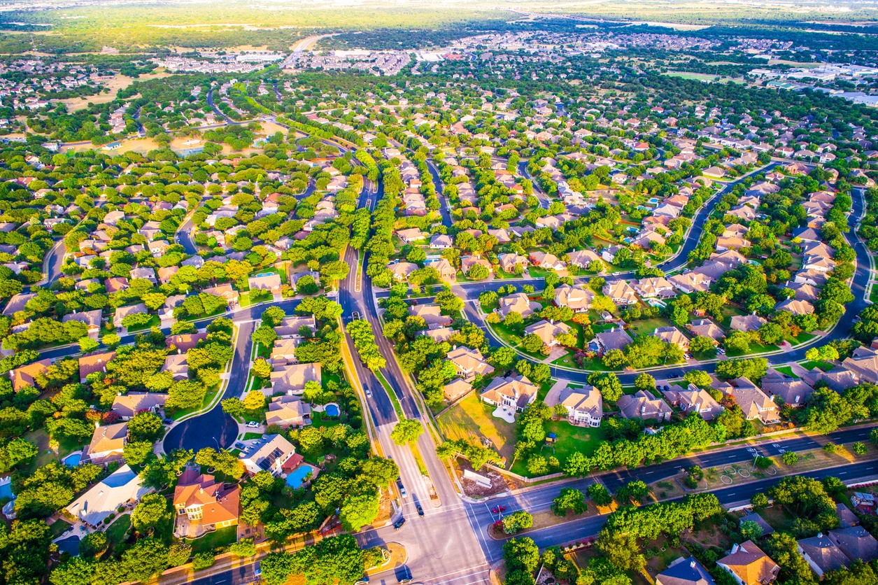 An aerial view shows thousands of modern homes in a vast Round Rock, Texas, suburban neighborhood at sunset