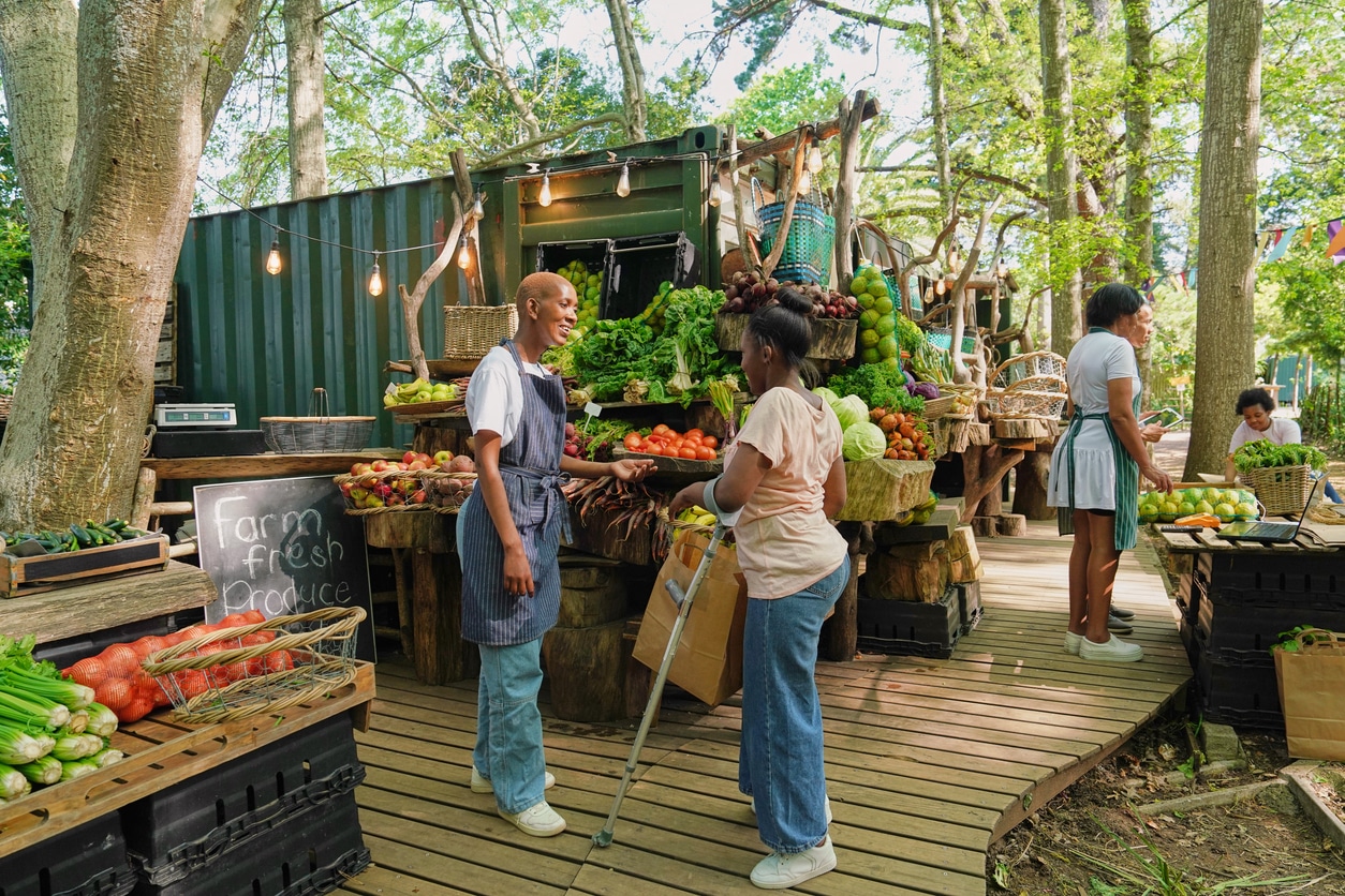 Shopper speaking to a store attendant at an outdoor market browse a vibrant display of fresh organic produce