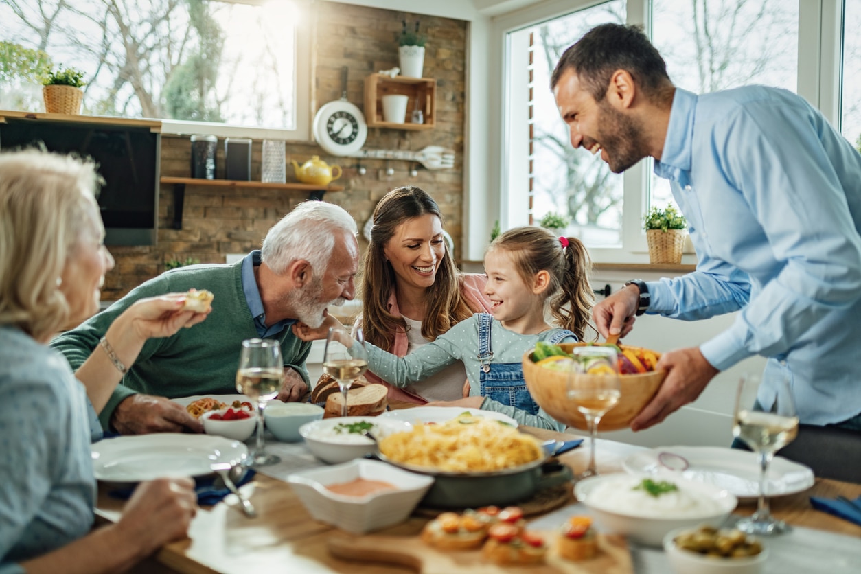 Happy extended family having fun during family lunch in dining room. A happy multi-generational family enjoys a meal together at a dining table after moving to be closer to family