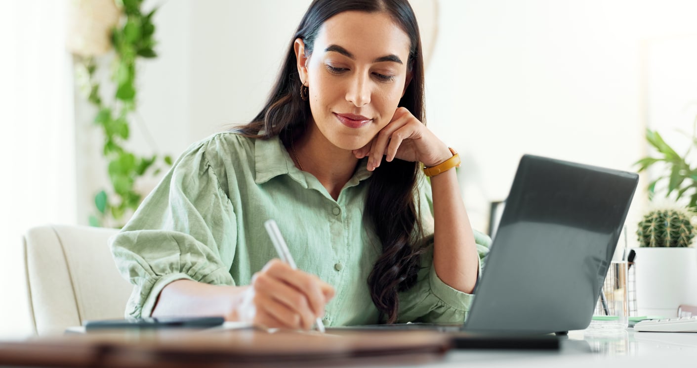 A woman in a green shirt smiles at a desk while planning a move to another state to start over