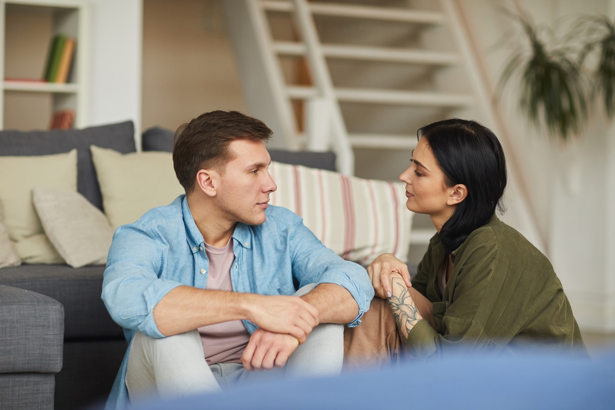 Young Couple Staying Home A young couple sits on the floor of a living room having a serious conversation about moving for love