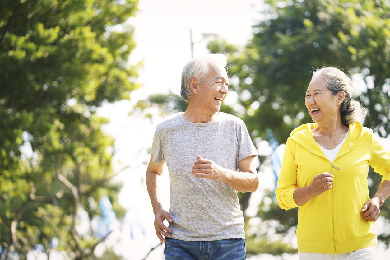 An elderly couple running and laughing together outdoors