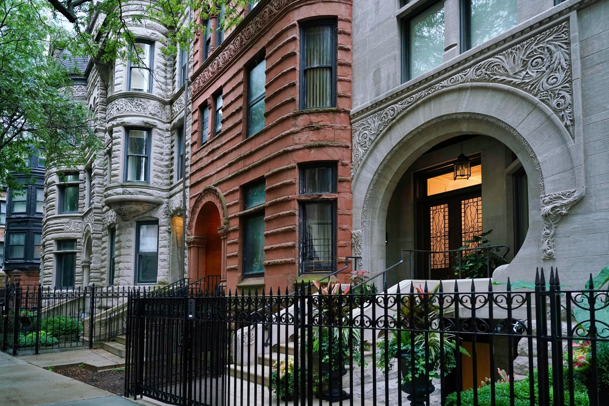 Historic Chicago greystone and brick row houses with ornate stone carvings and black wrought iron fencing