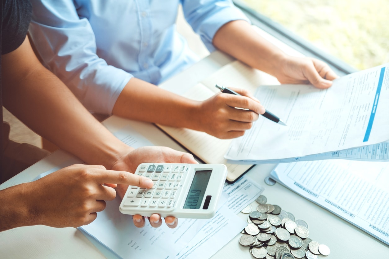 Two people review paperwork and use a calculator as they plan moving from NYC to LA
