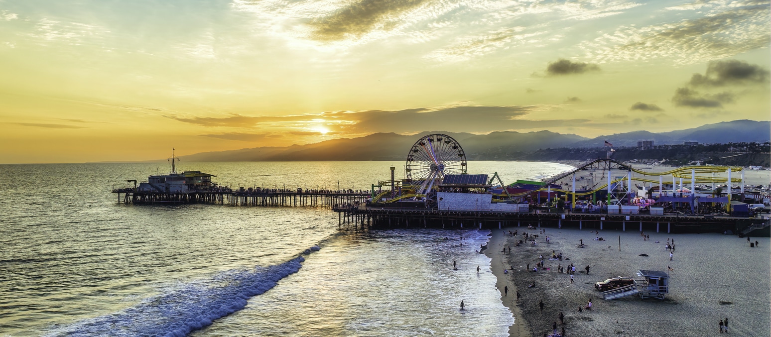 A Los Angeles beach with pier and ferris wheel at sunset, a welcoming sight for those moving from New York to LA
