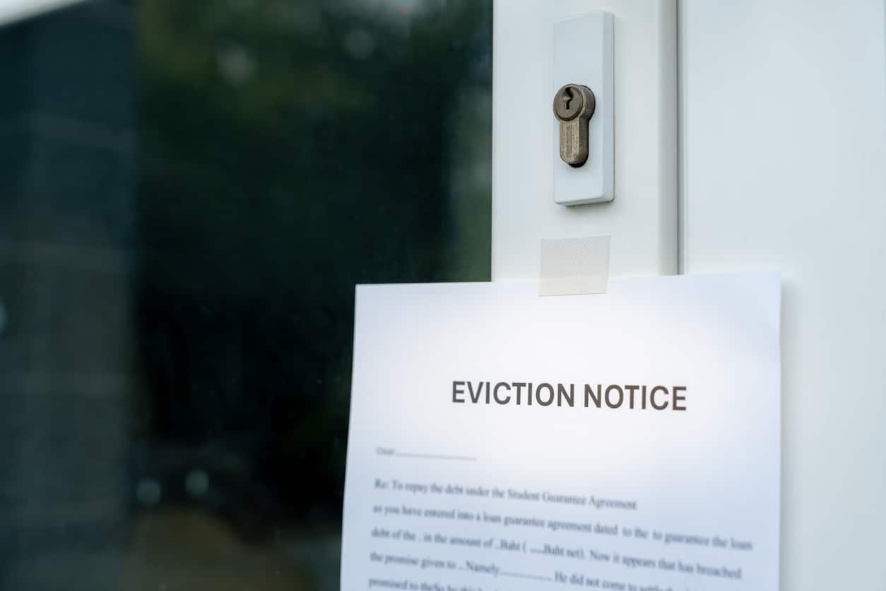 An eviction notice document taped to a residential door, indicating a legal process