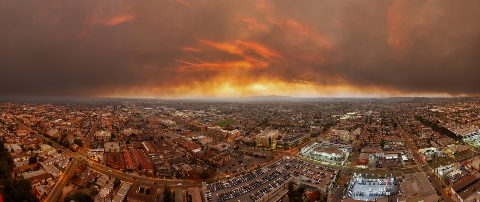 An aerial view of Los Angeles under thick smoke from a nearby wildfire at sunset
