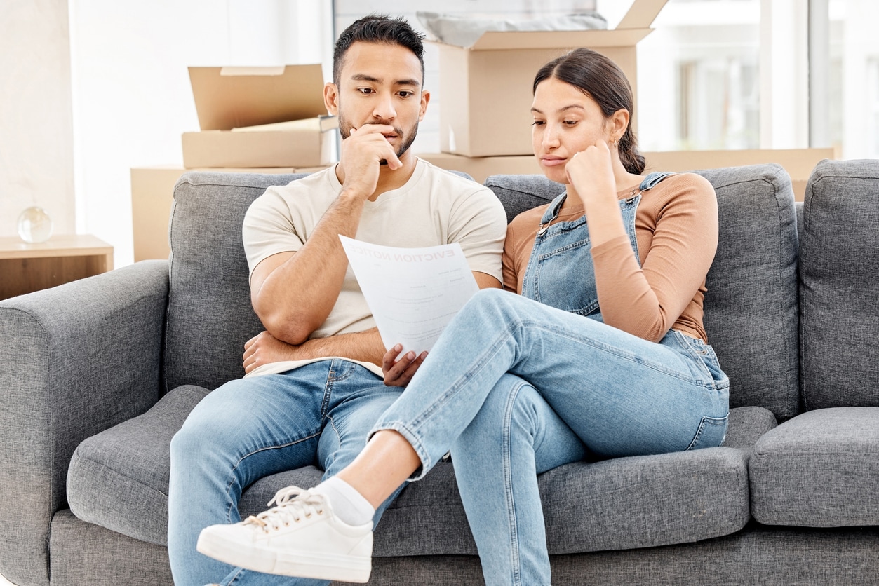 A man and woman sit on a gray sofa, planning their move to Phoenix from San Diego