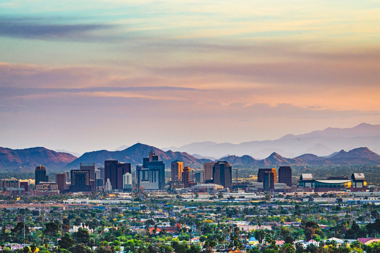 A wide skyline of a Phoenix, Arizona, with tall buildings and a background of a hazy mountain range