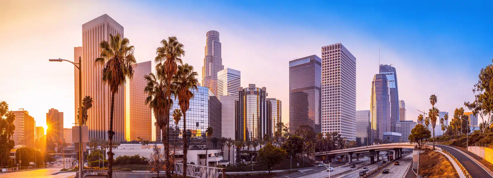 The sun sets over the L.A. skyline and a busy freeway, a sight welcoming those moving from San Francisco to Los Angeles