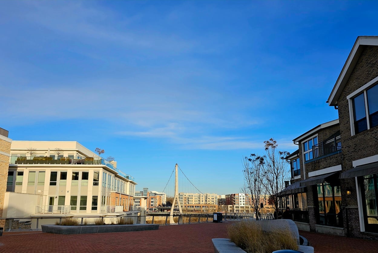 Dublin link bridge- Dublin Ohio USA Modern multi-story buildings and a brick plaza lead toward a white suspension bridge in a Columbus neighborhood