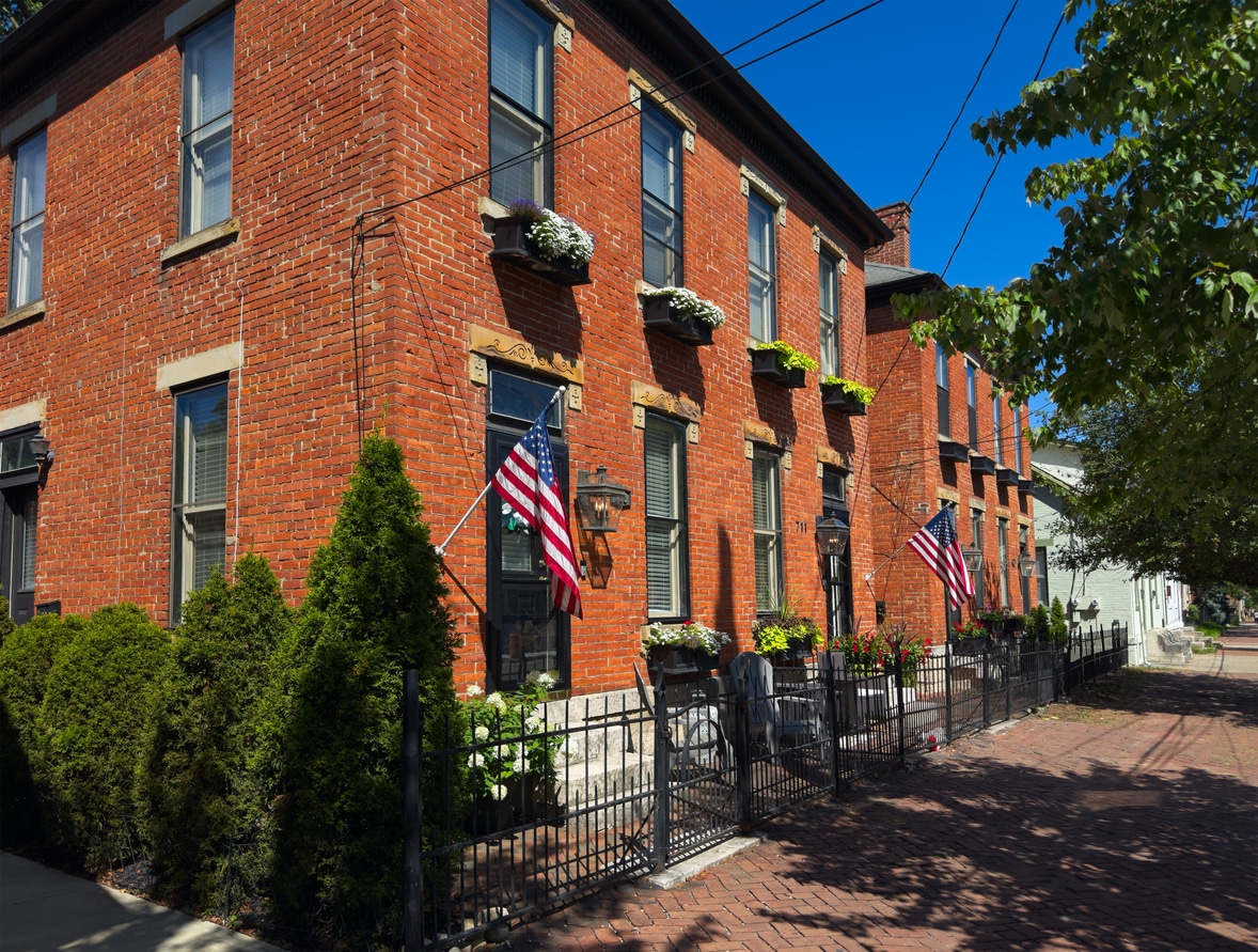 German Village scene Historic red brick townhomes in Columbus neighborhood, with flower boxes and American flags under a clear blue sky
