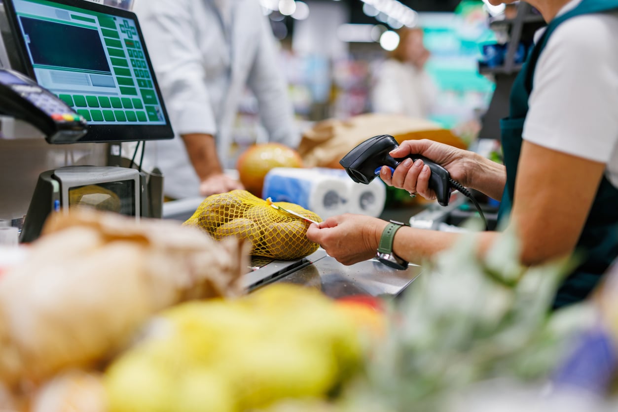 Cashier scanning groceries at checkout in supermarket A grocery store cashier uses a handheld scanner to scan groceries in NYC