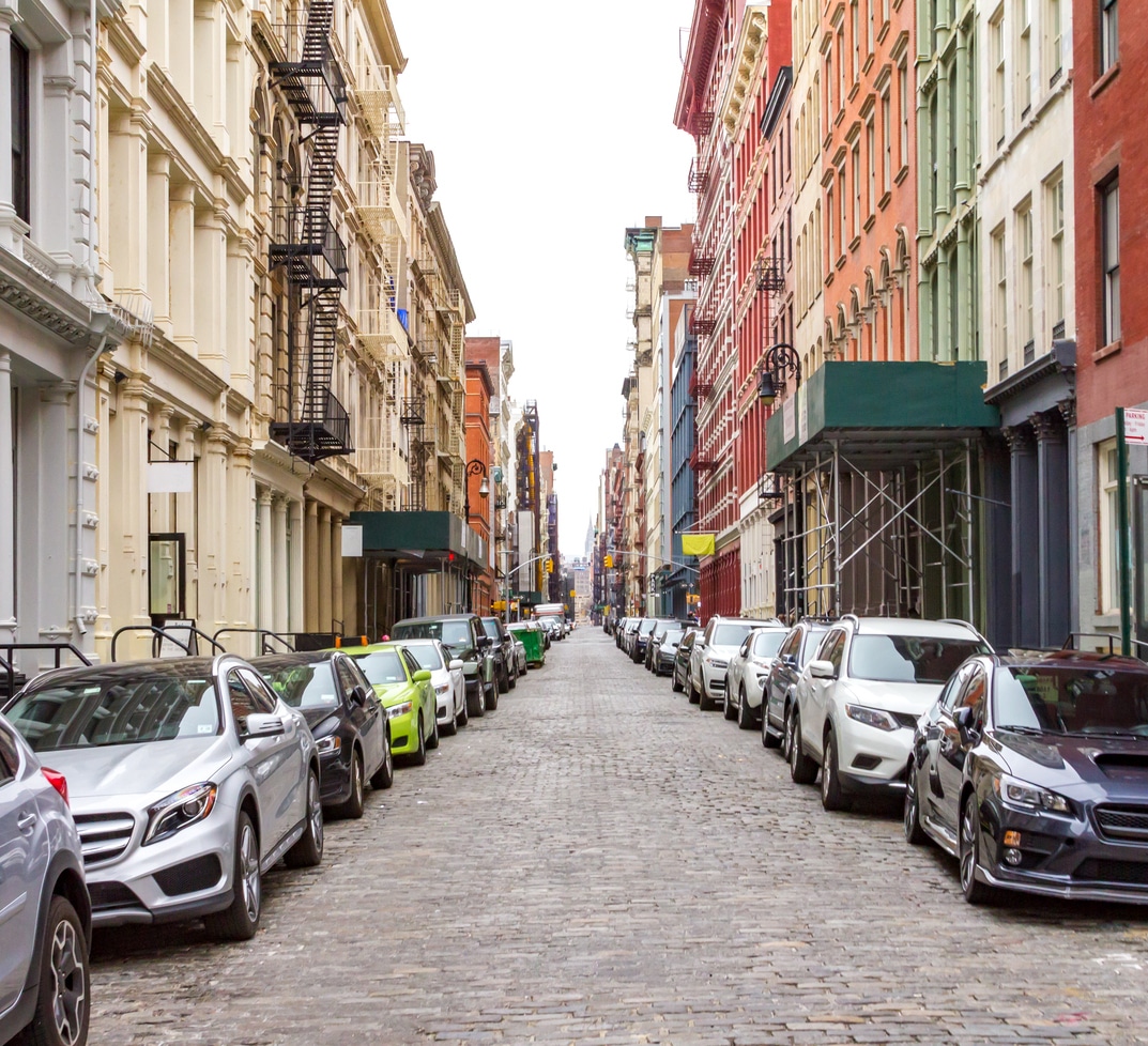New York City cobblestone street scene in SoHo Cars parked along a narrow New York City street lined with apartment buildings