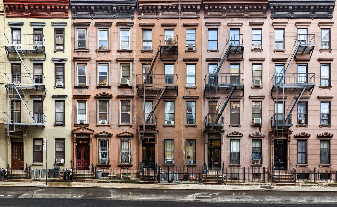Block of historic apartment buildings crowded together on West 49th Street in the Hell's Kitchen neighborhood of New York City Five colorful New York City brownstone homes, an example of the real estate available to those moving from Miami to NYC