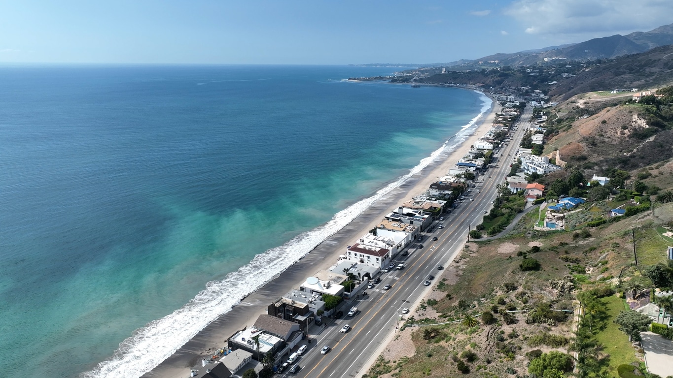 Malibu Beach at Los Angeles in California United States. Aerial coastal view of a Los Angeles beach next to a highway lined with houses and green hills