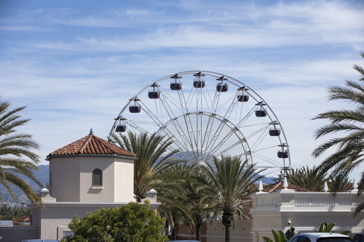 A large Ferris wheel rises behind palm trees, a highlight for families moving to Orange County