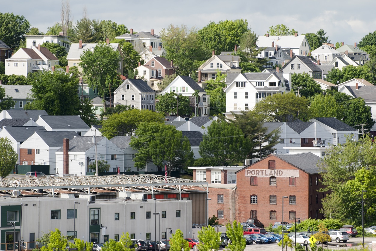A row of homes with colorful facades and green lawns, typical residential options for those living in Portland, Maine