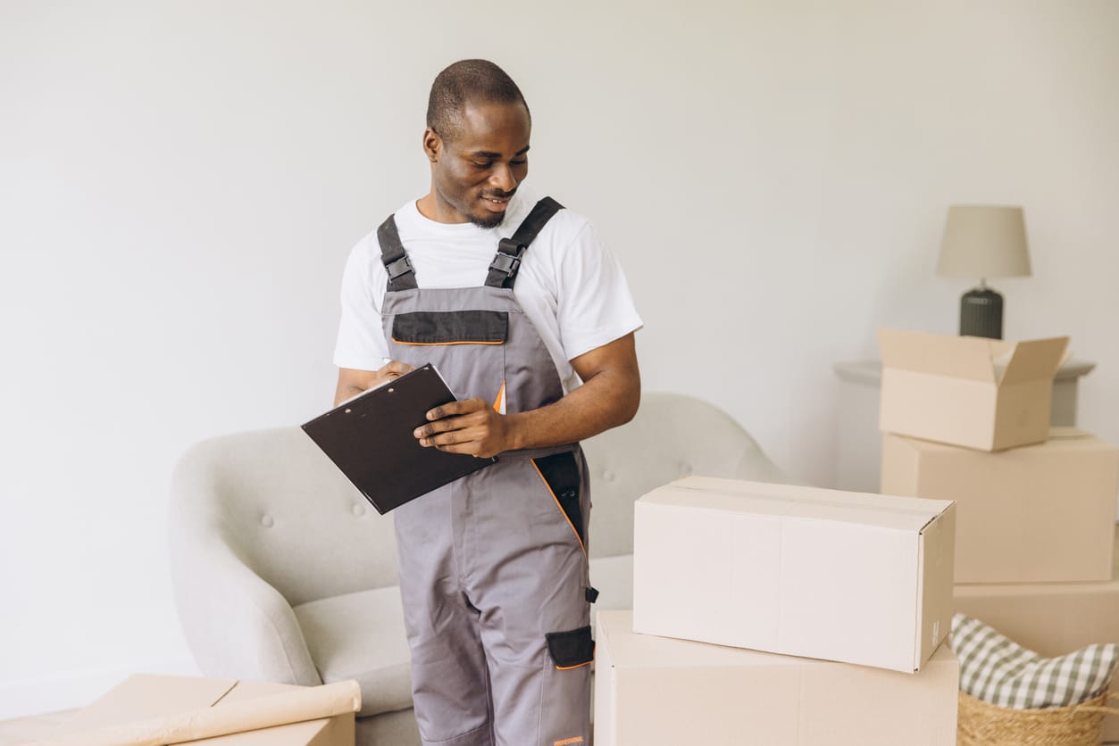 A mover with a beard reviews a printed checklist, which contains questions to ask moving companies