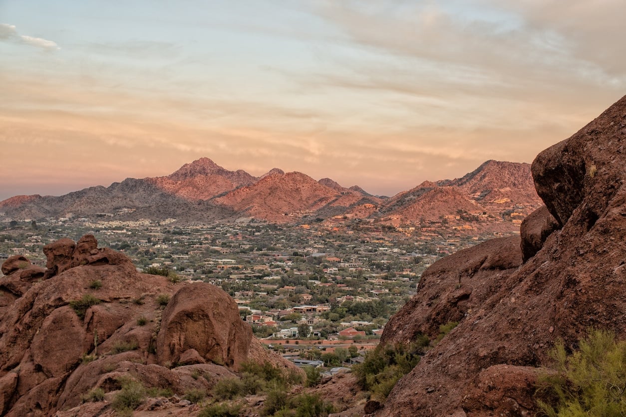 A wide view of a desert valley filled with the best Scottsdale neighborhoods under a soft sunset sky