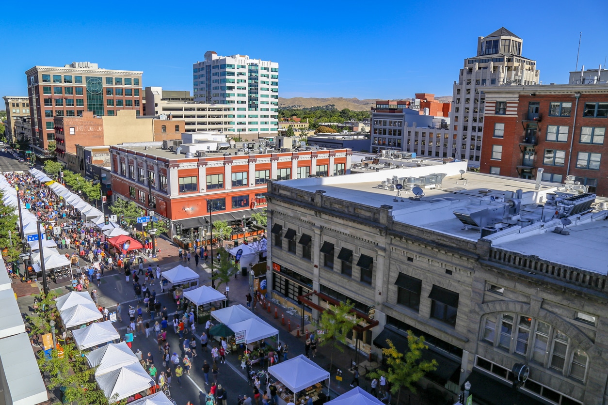 High-angle view of a bustling Idaho outdoor street market lined with white tents on a sunny day