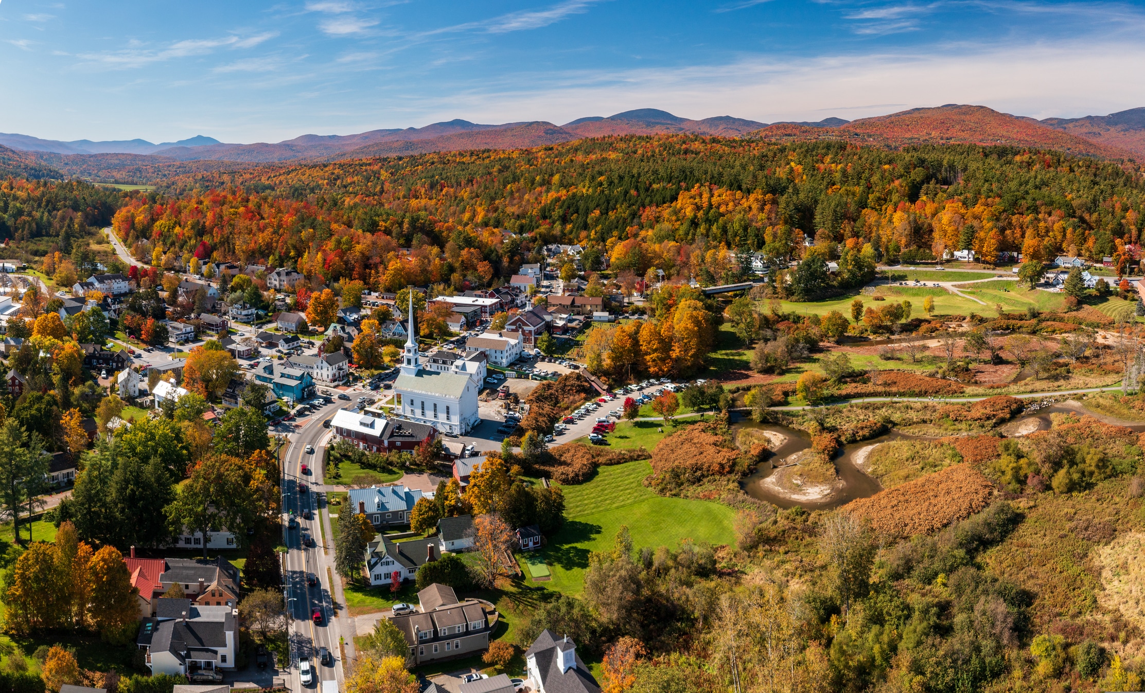 Aerial view of the town of Stowe in the fall Aerial view of a coastal New England town with white buildings and church steeples surrounded by fall foliage