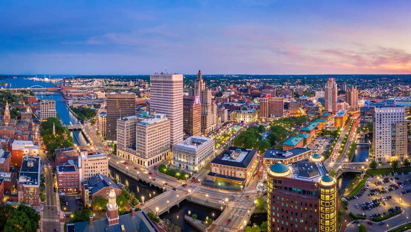 Aerial panorama of Providence, Rhode Island Aerial view of a bustling New England skyline at dusk with lit streets, bridges over a river, and a colorful sunset sky
