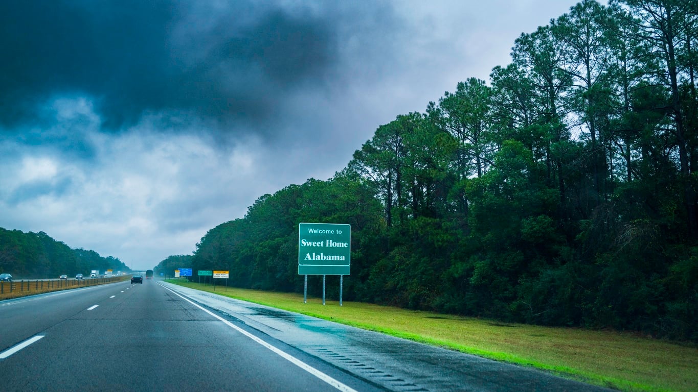A green highway sign reading "Welcome to Sweet Home Alabama,” welcoming those moving to Alabama