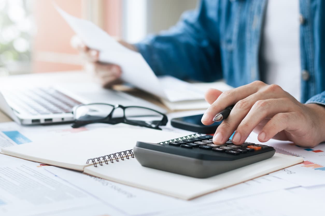 A close-up of a person using a calculator to find out the cost of moving without a job